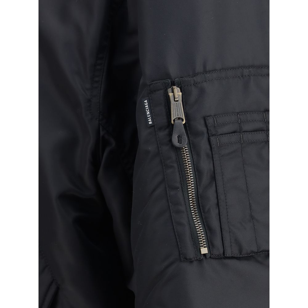 Zipped Standard BomberThe Bomber Standard by Balenciaga reimagines a streetwear classic with the brand’s bold aesthetic. Crafted from recycled satin polyamide, it features a zip closure, two flap pockets with snap buttons at the front, and the iconic zip
