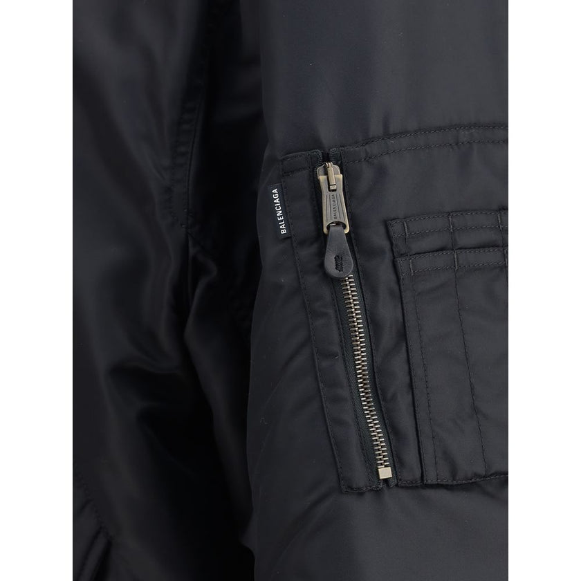 Zipped Standard BomberThe Bomber Standard by Balenciaga reimagines a streetwear classic with the brand’s bold aesthetic. Crafted from recycled satin polyamide, it features a zip closure, two flap pockets with snap buttons at the front, and the iconic zip