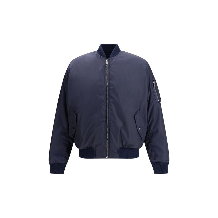 Blue Recycled Polyamide BomberThe Bomber Jacket by Prada blends urban elegance with refined detailing. Featuring a regular fit, it is defined by rib-knit collar and cuffs for comfort and a subtle sporty touch. The zip closure and flap pockets with button