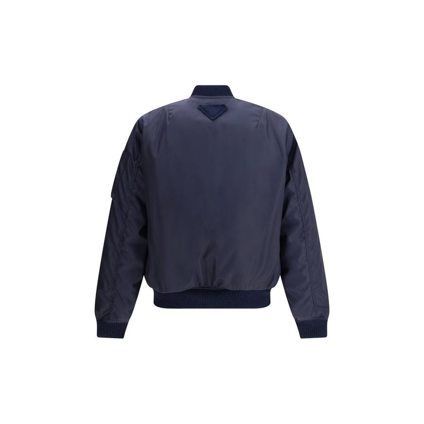 Blue Recycled Polyamide BomberThe Bomber Jacket by Prada blends urban elegance with refined detailing. Featuring a regular fit, it is defined by rib-knit collar and cuffs for comfort and a subtle sporty touch. The zip closure and flap pockets with button