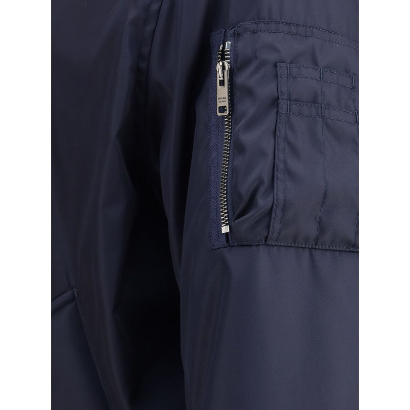 Blue Recycled Polyamide BomberThe Bomber Jacket by Prada blends urban elegance with refined detailing. Featuring a regular fit, it is defined by rib-knit collar and cuffs for comfort and a subtle sporty touch. The zip closure and flap pockets with button