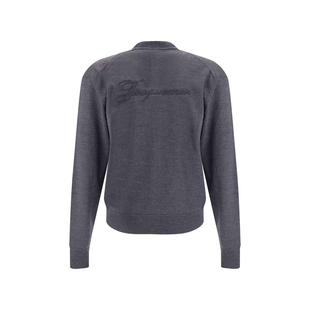 Gray Merino Wool CardiganThe merino Wool Cardigan by Jacquemus blends elegance with comfort, embodying a timeless appeal. Its V-neckline and front button closure echo classic tailoring, while ribbed hem and cuffs provide structure and refinement. At the b
