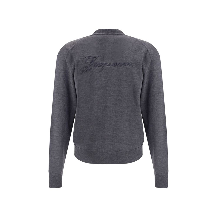 Gray Merino Wool CardiganThe merino Wool Cardigan by Jacquemus blends elegance with comfort, embodying a timeless appeal. Its V-neckline and front button closure echo classic tailoring, while ribbed hem and cuffs provide structure and refinement. At the b