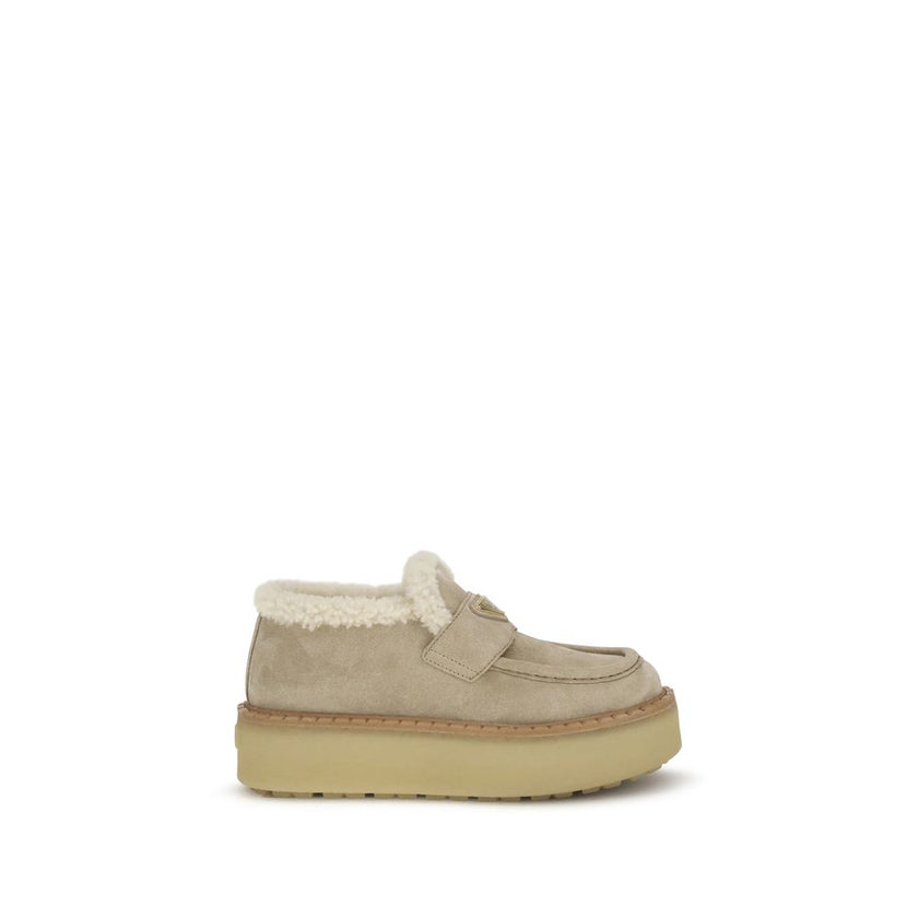 Beige Calf Leather Bos Taurus Platform LoafersSuede Loafers by Prada combine comfort and style in a bold design. Featuring a platform sole and round toe, they feature a soft shearling-lined interior for a snug fit. The upper tray is embellished with the i