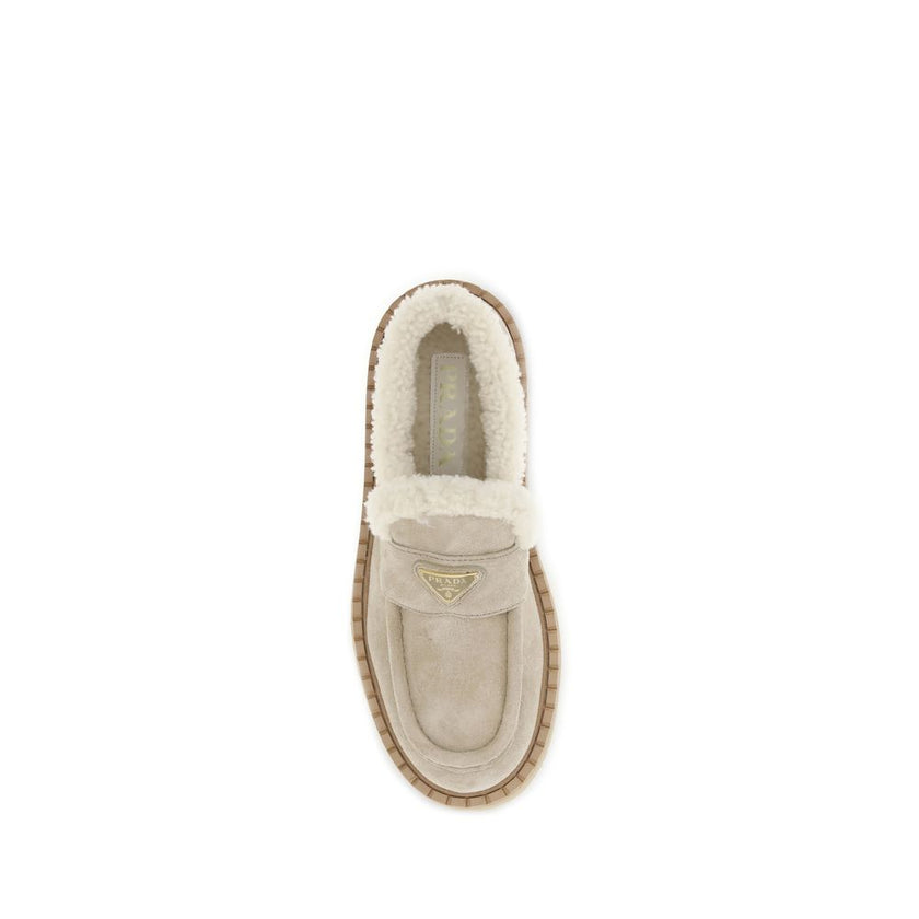 Beige Calf Leather Bos Taurus Platform LoafersSuede Loafers by Prada combine comfort and style in a bold design. Featuring a platform sole and round toe, they feature a soft shearling-lined interior for a snug fit. The upper tray is embellished with the i