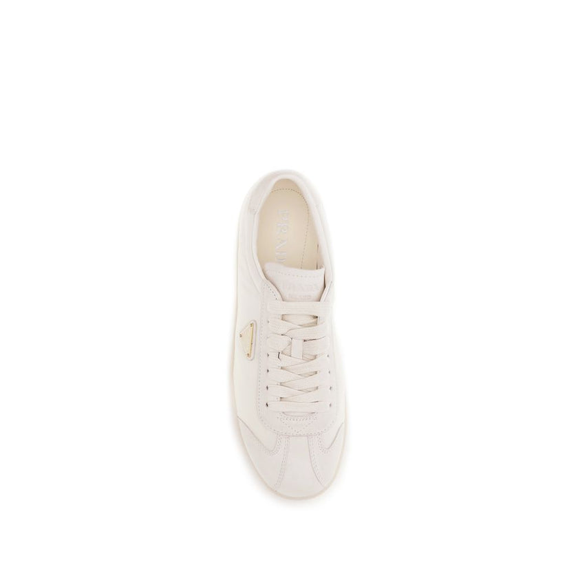 Cream Leather Low Top SneakersLeather Sneakers by Prada combine contemporary style with everyday comfort. Featuring a flat rubber sole and round toe, they are distinguished by the iconic triangular side-applied plaque and tone-on-tone logo on the back, ad