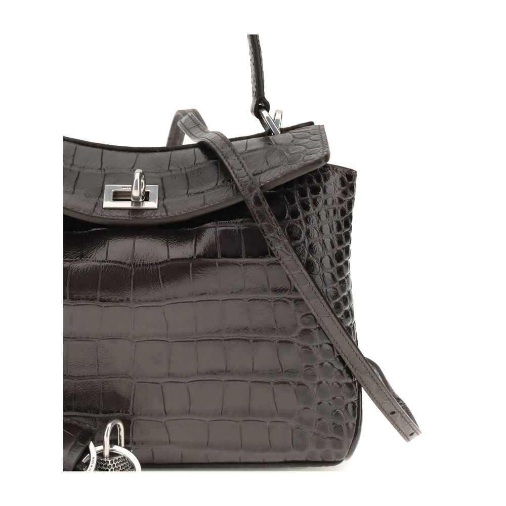 Brown Calf Leather Bos Taurus HandbagRodeo mini Handbag by Baleciaga is a luxury accessory with a bold and shiny character. Made of calfskin leather with crocodile-effect processing, it is embellished with rhinestones and antiqued silver details that enha