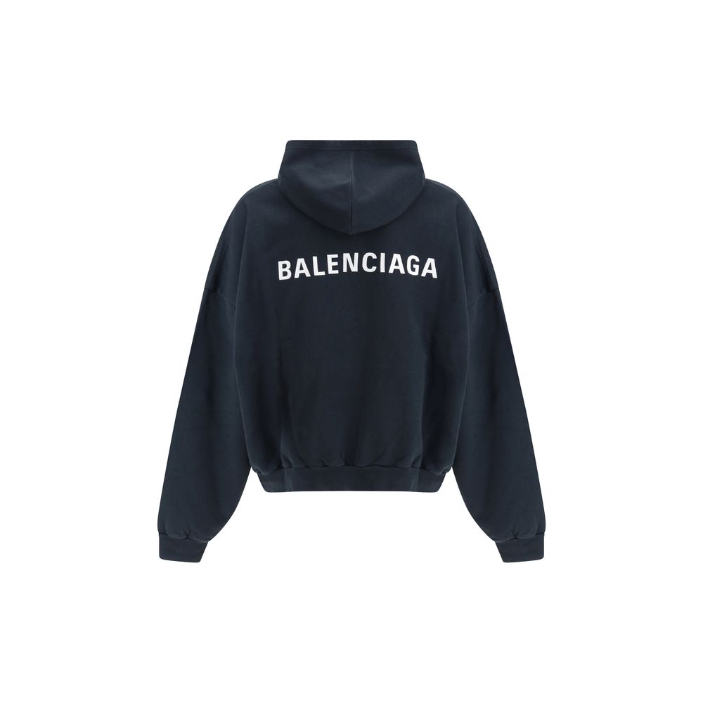 Black Cotton SweatshirtThe Hoodie by Balenciaga blends comfort with iconic design. Crafted from medium fleece, it features a relaxed silhouette with dropped shoulders and a functional kangaroo pocket. Elasticated cuffs and hem ensure a defined fit, while