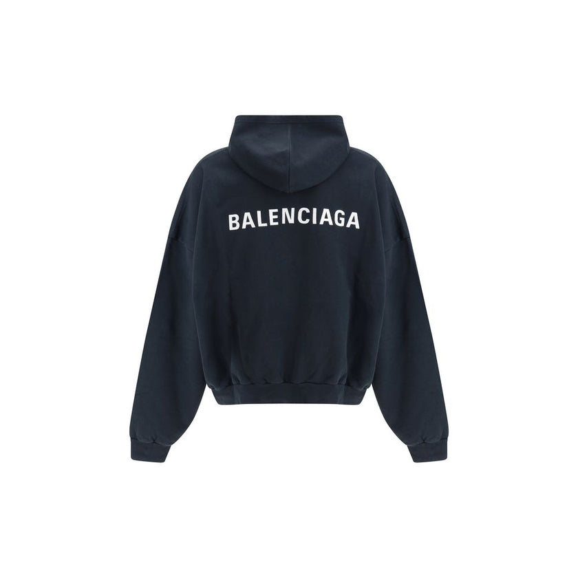 Black Cotton SweatshirtThe Hoodie by Balenciaga blends comfort with iconic design. Crafted from medium fleece, it features a relaxed silhouette with dropped shoulders and a functional kangaroo pocket. Elasticated cuffs and hem ensure a defined fit, while