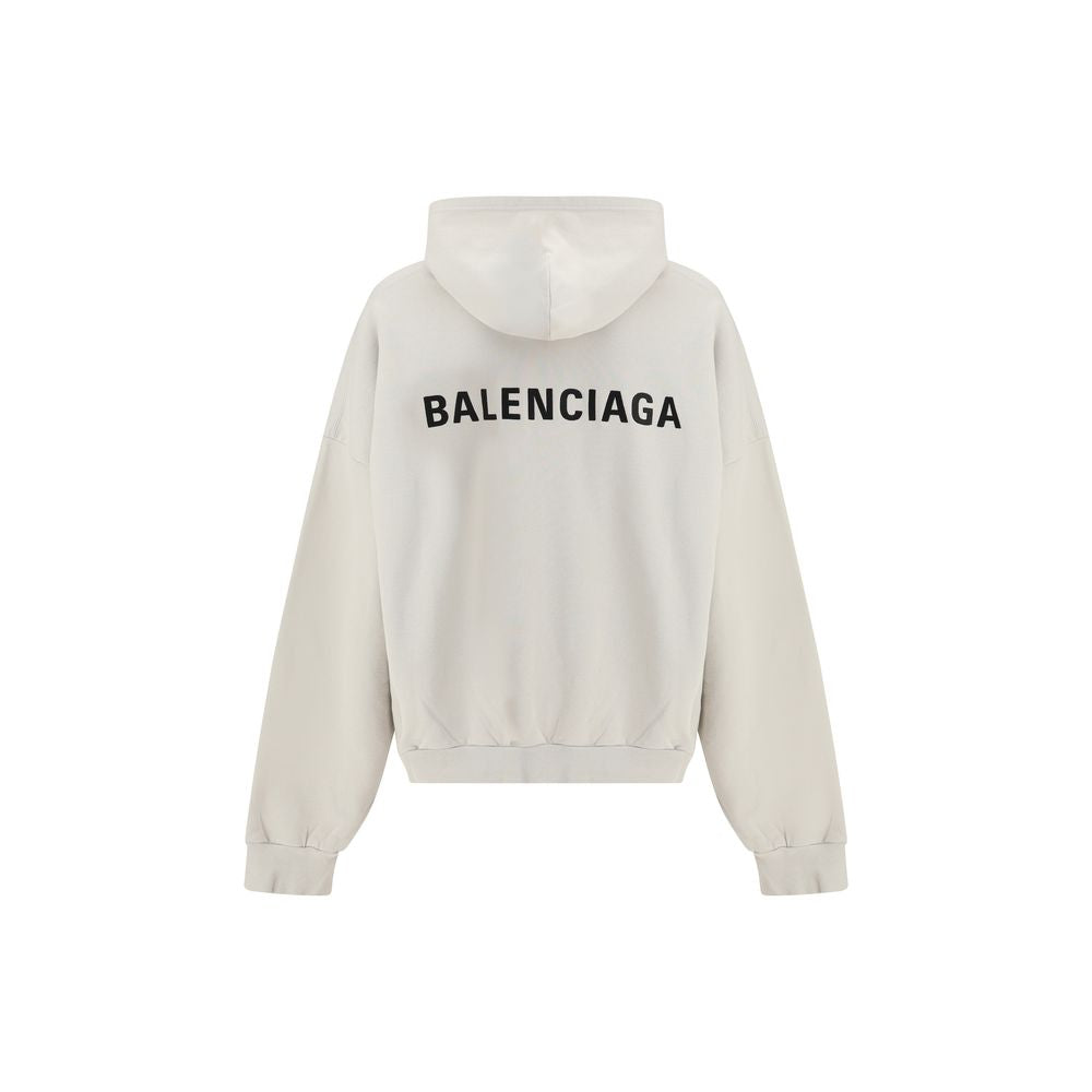 White Cotton SweatshirtThe Hoodie by Balenciaga blends comfort with iconic design. Crafted from medium fleece, it features a relaxed silhouette with dropped shoulders and a functional kangaroo pocket. Elasticated cuffs and hem ensure a defined fit, while