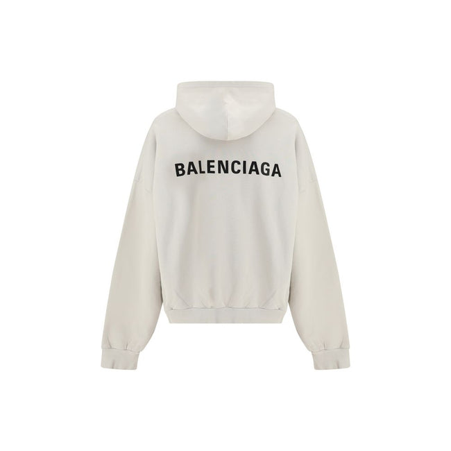 White Cotton SweatshirtThe Hoodie by Balenciaga blends comfort with iconic design. Crafted from medium fleece, it features a relaxed silhouette with dropped shoulders and a functional kangaroo pocket. Elasticated cuffs and hem ensure a defined fit, while