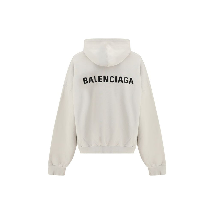 White Cotton SweatshirtThe Hoodie by Balenciaga blends comfort with iconic design. Crafted from medium fleece, it features a relaxed silhouette with dropped shoulders and a functional kangaroo pocket. Elasticated cuffs and hem ensure a defined fit, while