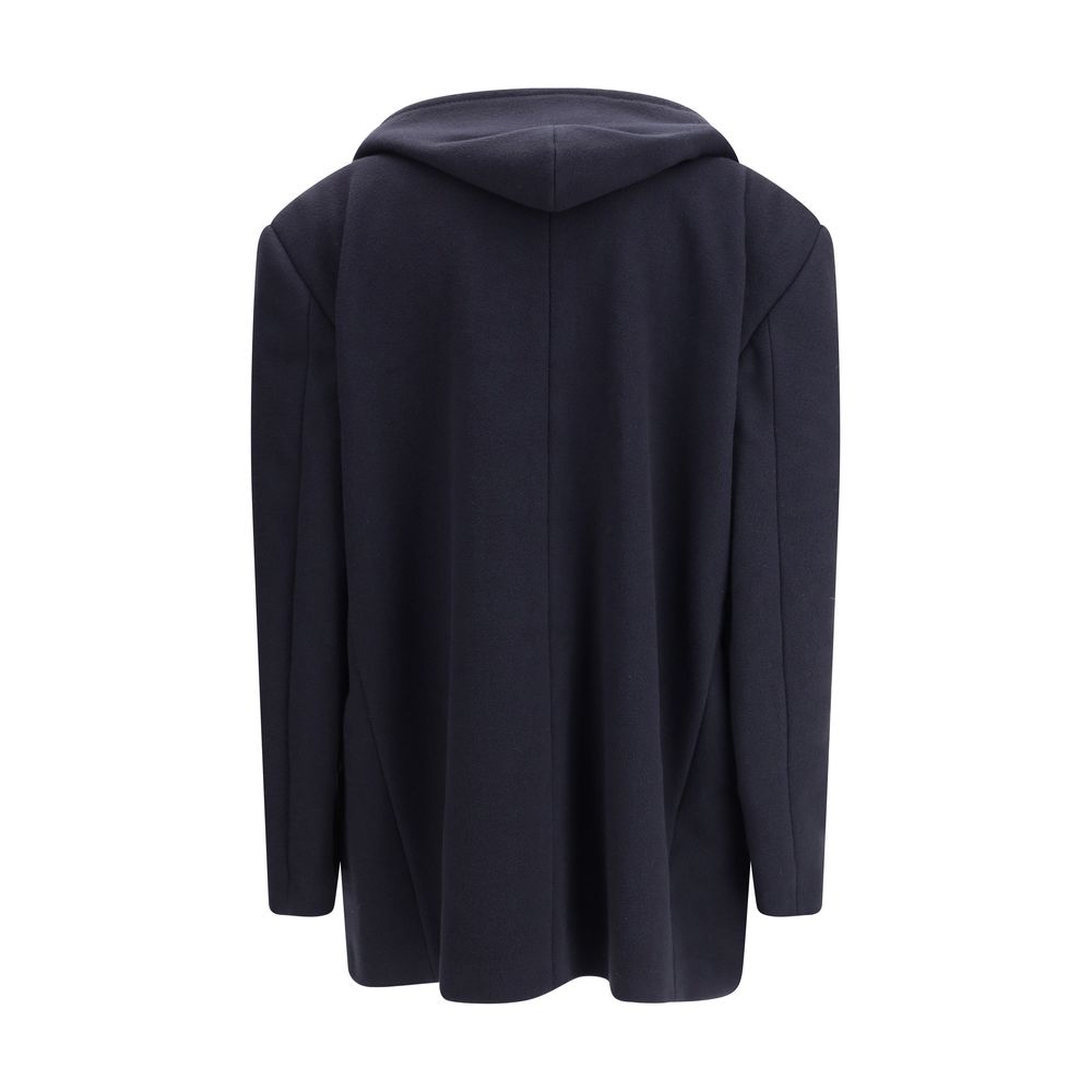 Hooded Short CoatThe hooded short Coat by Balenciaga blends tailored refinement with the brand’s contemporary edge. Crafted from dark navy brushed wool, it features a structured cut enhanced by shoulder pads and peak lapels, giving the silhouette a bold p