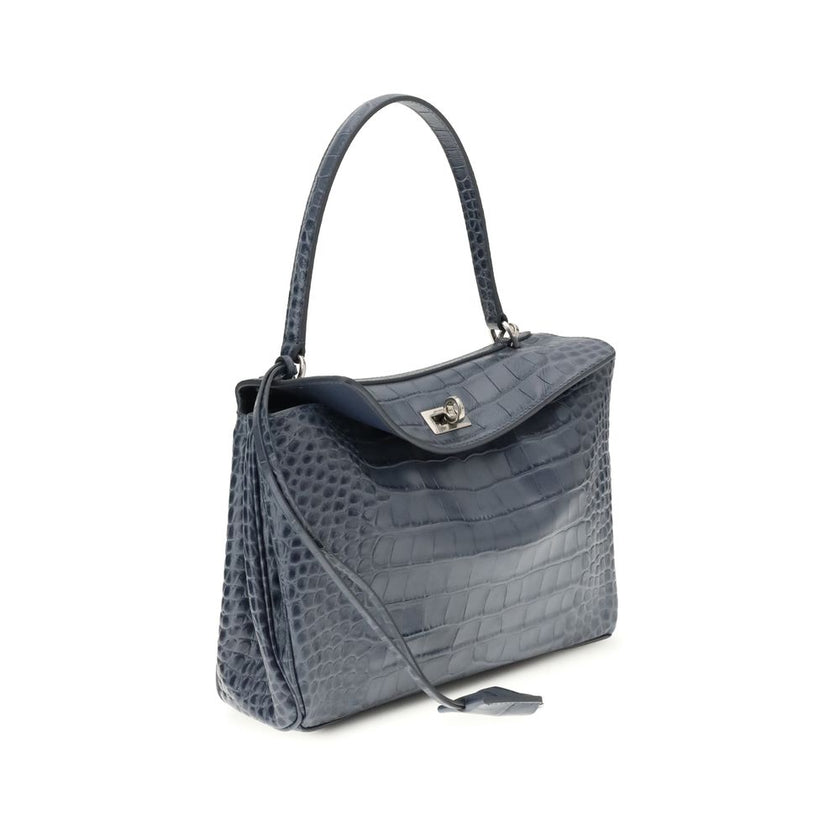 Light Blue Calf Leather Bos Taurus HandbagSmall Rodeo Handbag by Balenciaga is a structured and refined model made of calfskin with crocodile-effect processing. Equipped with a top handle and removable shoulder strap, it features iconic details such as a