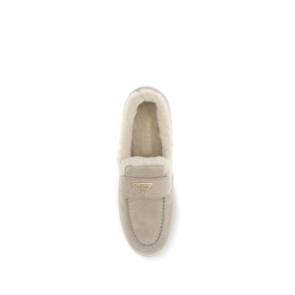 Beige Leather Slip-On LoafersSuede and sheepskin Loafers by Prada combine elegance and comfort in a modern, streamlined silhouette. The upper is embellished with a leather horsebit and a pinch-stitched basin, hallmarks of painstaking craftsmanship. The sh