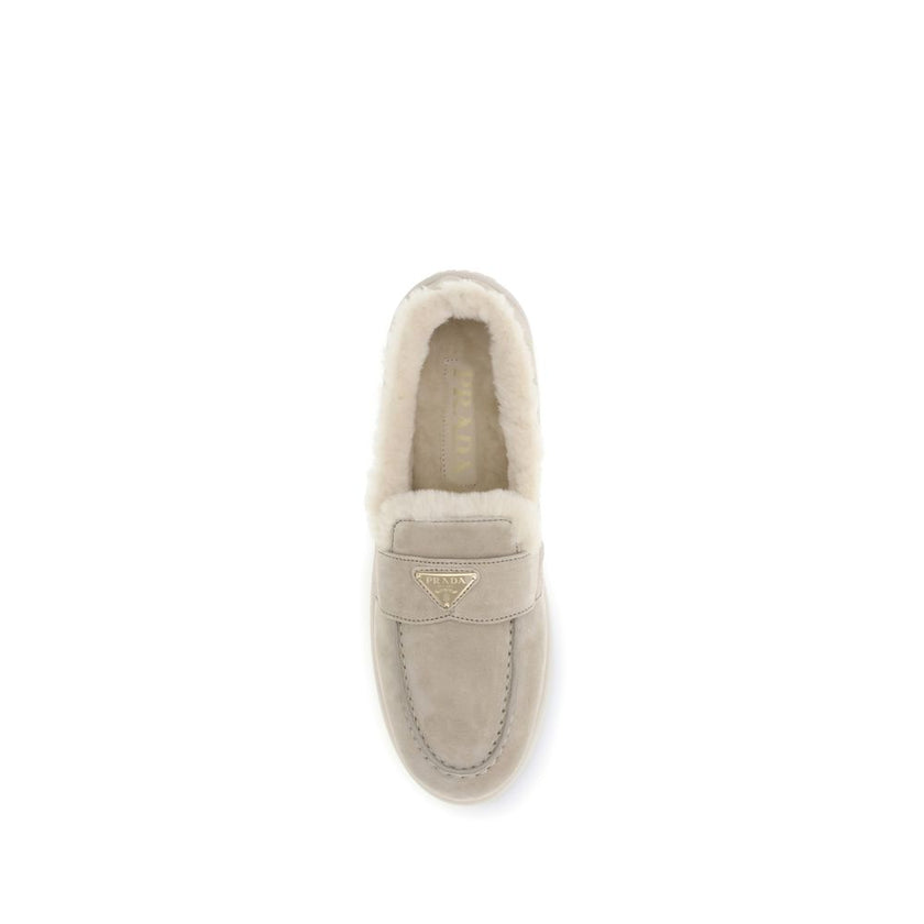Beige Leather Slip-On LoafersSuede and sheepskin Loafers by Prada combine elegance and comfort in a modern, streamlined silhouette. The upper is embellished with a leather horsebit and a pinch-stitched basin, hallmarks of painstaking craftsmanship. The sh