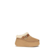 Nama Wedge MulesThe Nama Wedge Mules by Chloé blend casual elegance with artisanal mastery. Crafted from suede calfskin and shearling, they feature a leather strap with the House’s signature Paddington buckle. The lightweight wedge, made from recycled mat