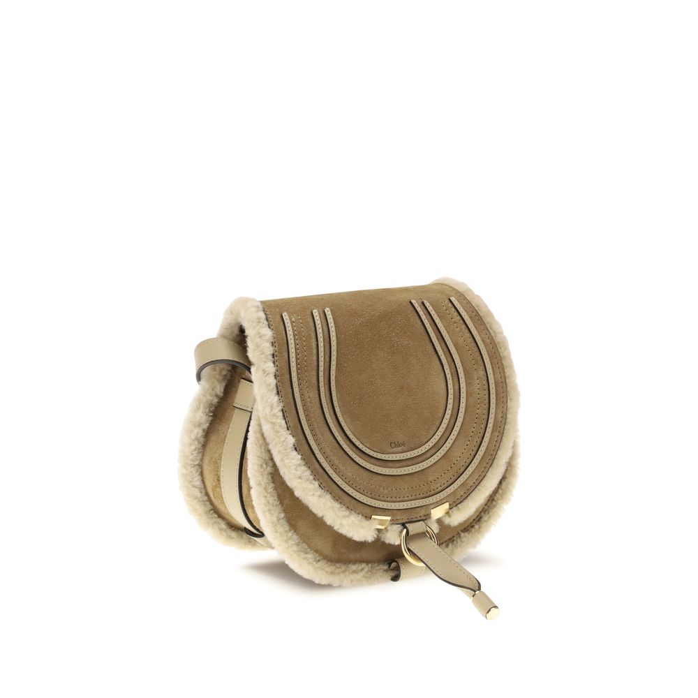 Beige Calf Leather Bos Taurus Shoulder BagSmall Saddle Marcie Shoulder Bag by Chloé reinterprets the house’s iconic equestrian aesthetic in a warm, textured key. Crafted in suede with shearling details, it is distinguished by its rounded silhouette and st