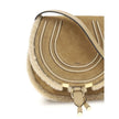 Beige Calf Leather Bos Taurus Shoulder BagSmall Saddle Marcie Shoulder Bag by Chloé reinterprets the house’s iconic equestrian aesthetic in a warm, textured key. Crafted in suede with shearling details, it is distinguished by its rounded silhouette and st