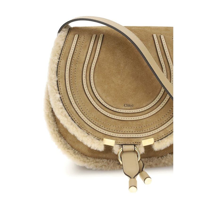 Beige Calf Leather Bos Taurus Shoulder BagSmall Saddle Marcie Shoulder Bag by Chloé reinterprets the house’s iconic equestrian aesthetic in a warm, textured key. Crafted in suede with shearling details, it is distinguished by its rounded silhouette and st