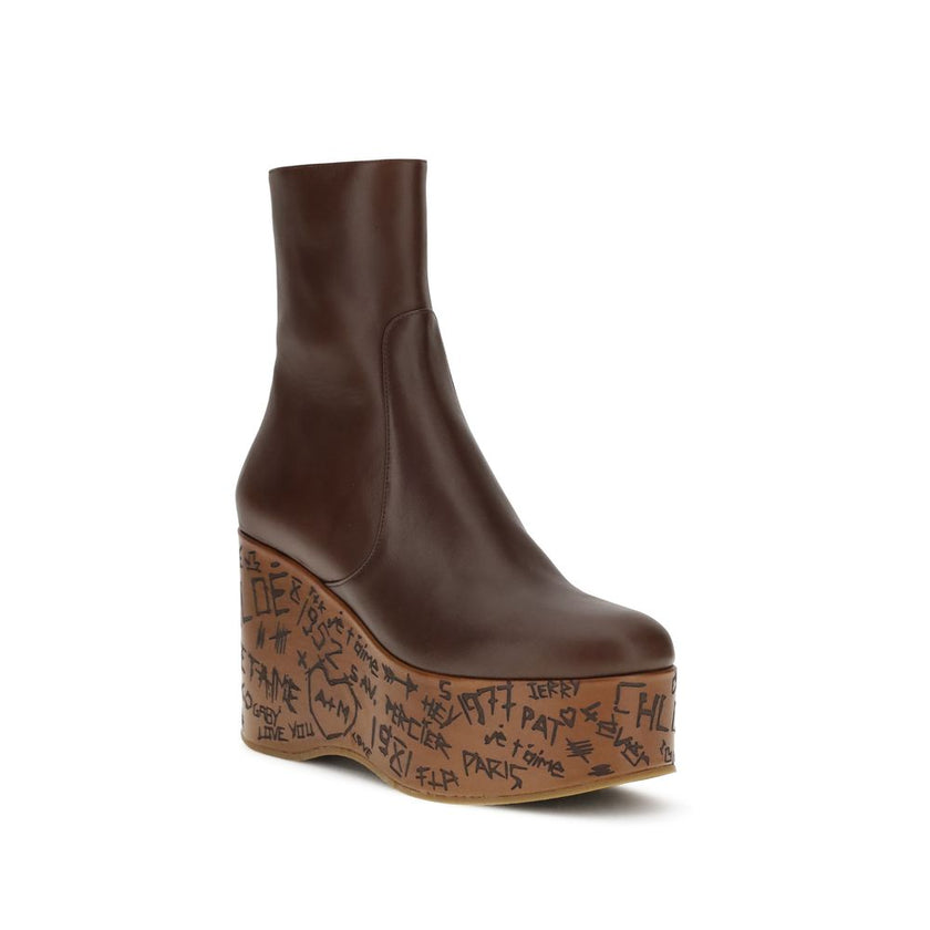 Brown Leather BootsMaxime wedge Ankle Boots by Chloé are a romantic homage to the Maison’s craftsmanship and identity. Made of glossy calfskin, they are distinguished by a wood-effect platform structure that recalls the natural and poetic aesthetic of a d
