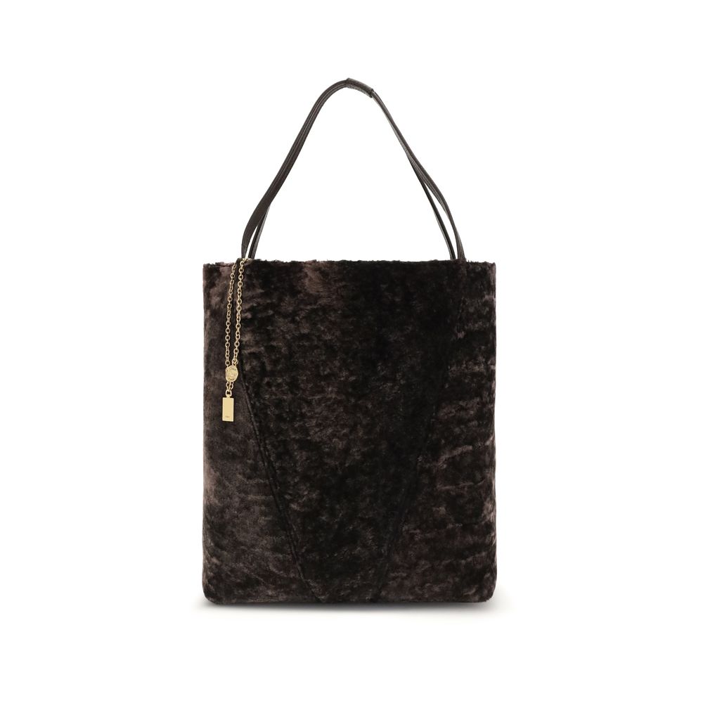 Brown Fur Shoulder BagLarge Spin Tote Bag by Chloè in soft shearling is distinguished by a compact, minimalist silhouette defined by clean graphic lines. The discreet elegance of the design is enhanced by a dangling chain with the iconic Chloé medals and
