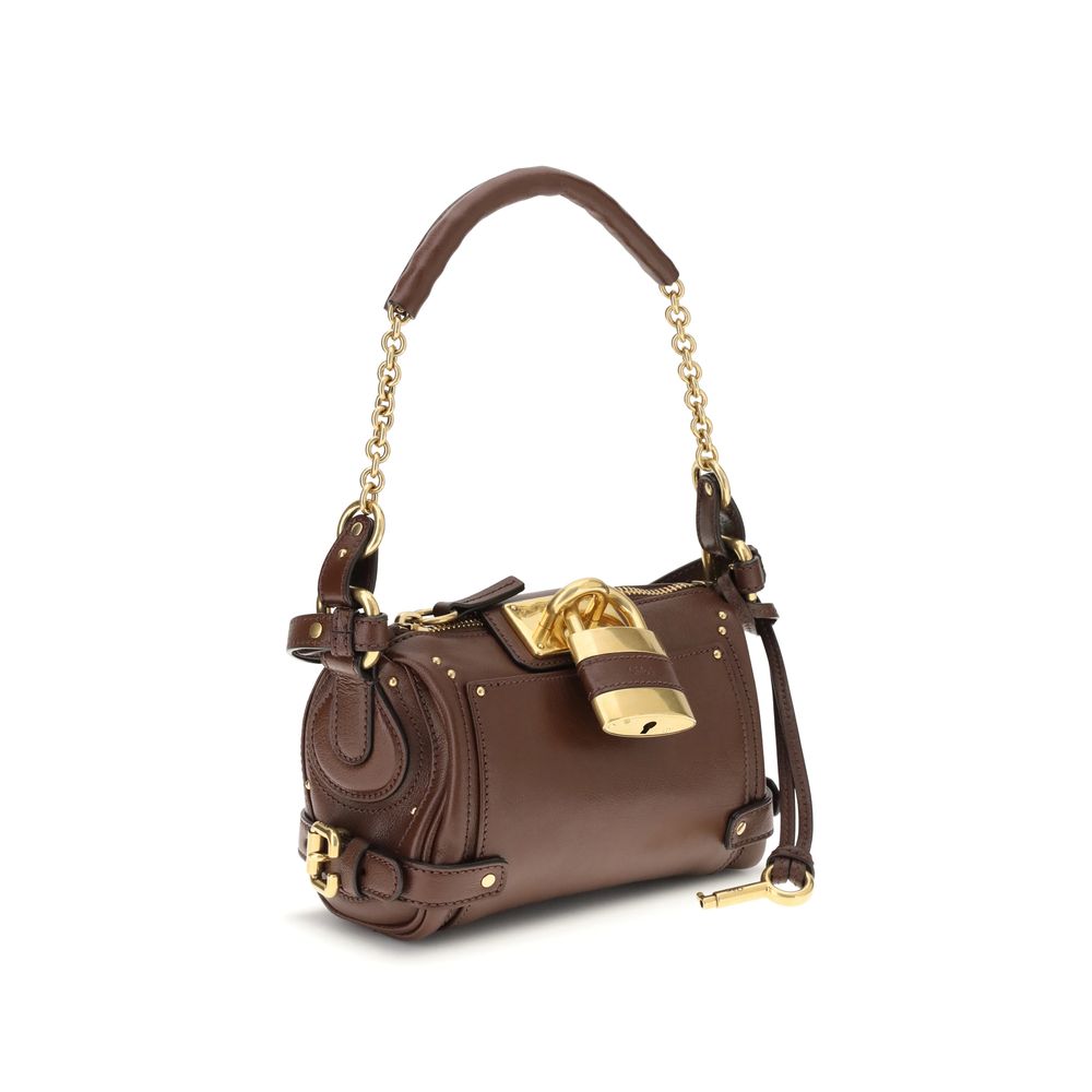 Paddington Shoulder BagPaddington Shoulder Bag by Chloé, crafted from soft garnet buffalo leather, stands out for its compact and flexible silhouette. Featuring a practical top zipper, it is embellished with iconic details such as an oversize padlock, C-s