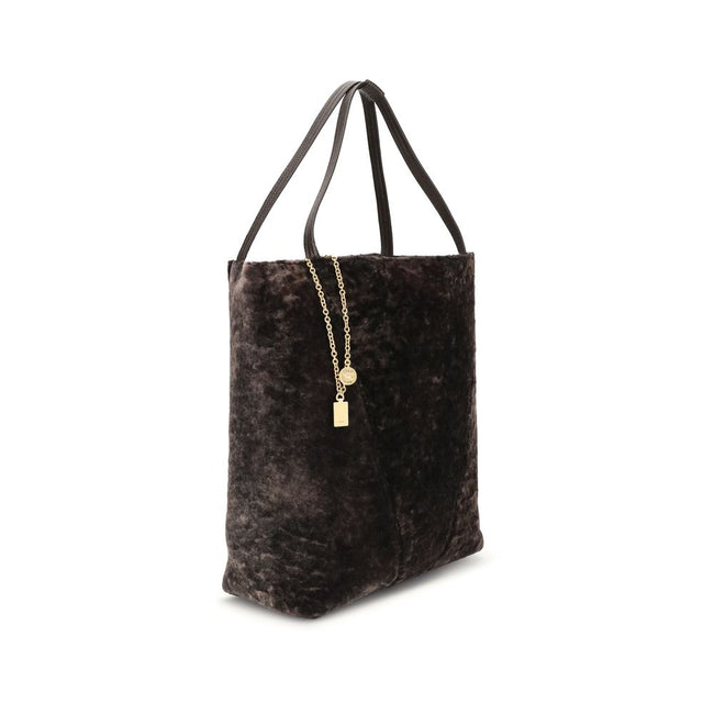 Brown Fur Shoulder BagLarge Spin Tote Bag by Chloè in soft shearling is distinguished by a compact, minimalist silhouette defined by clean graphic lines. The discreet elegance of the design is enhanced by a dangling chain with the iconic Chloé medals and
