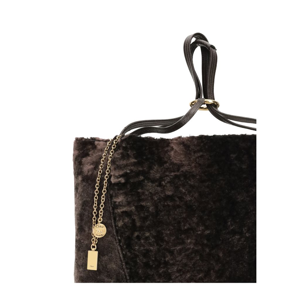 Brown Fur Shoulder BagLarge Spin Tote Bag by Chloè in soft shearling is distinguished by a compact, minimalist silhouette defined by clean graphic lines. The discreet elegance of the design is enhanced by a dangling chain with the iconic Chloé medals and