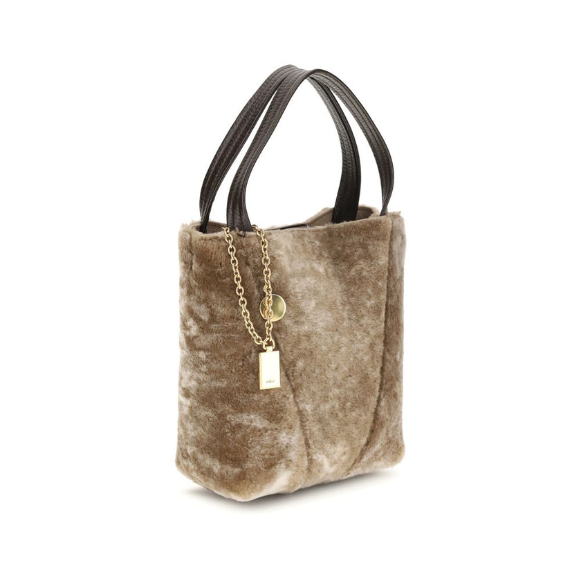 Beige Fur Shoulder BagSpin small Tote Bag by Chloè in soft shearling is distinguished by a compact, minimalist silhouette defined by clean graphic lines. The discreet elegance of the design is enhanced by a dangling chain with the iconic Chloé medals and