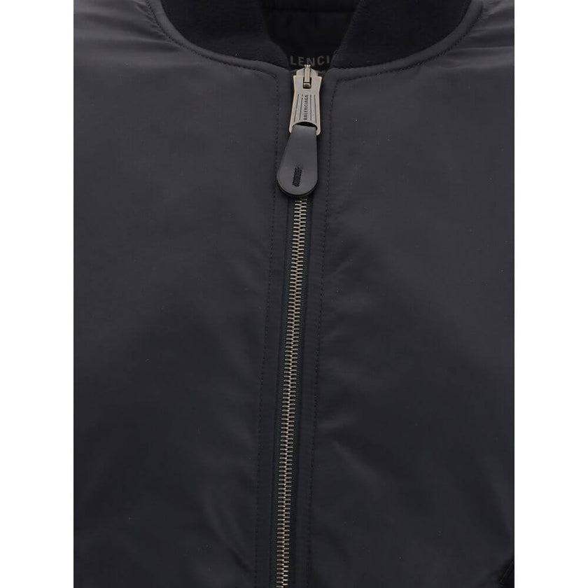 Black Polyamide BomberThe Standard Bomber offers a refined take on a timeless staple. Crafted from recycled satin-finish polyamide, it features ruched sleeves that add volume and character to the silhouette. A central zip closure and ribbed trims highligh