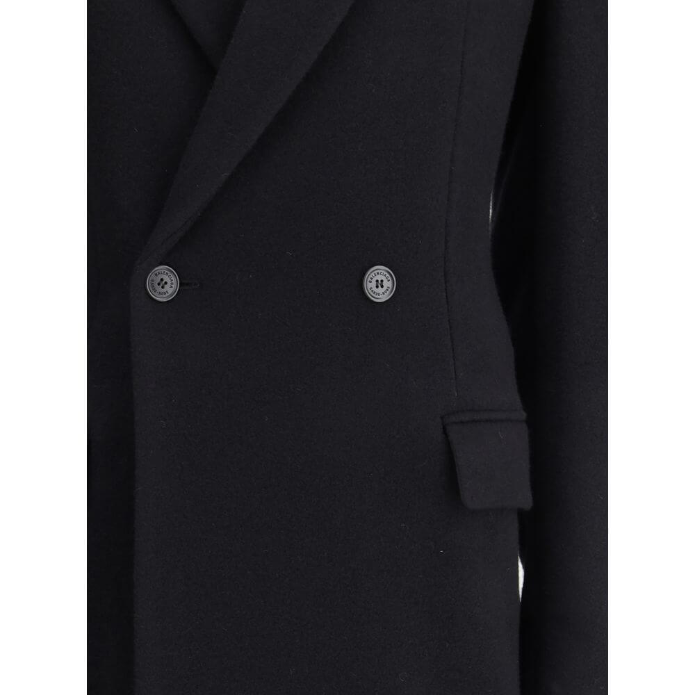 Black Wool CoatThe oversized double-breasted Coat by Balenciaga is an icon of contemporary elegance, blending sartorial precision with bold proportions. Crafted from a luxurious black wool and cashmere blend, it features a wide, structured silhouette enha