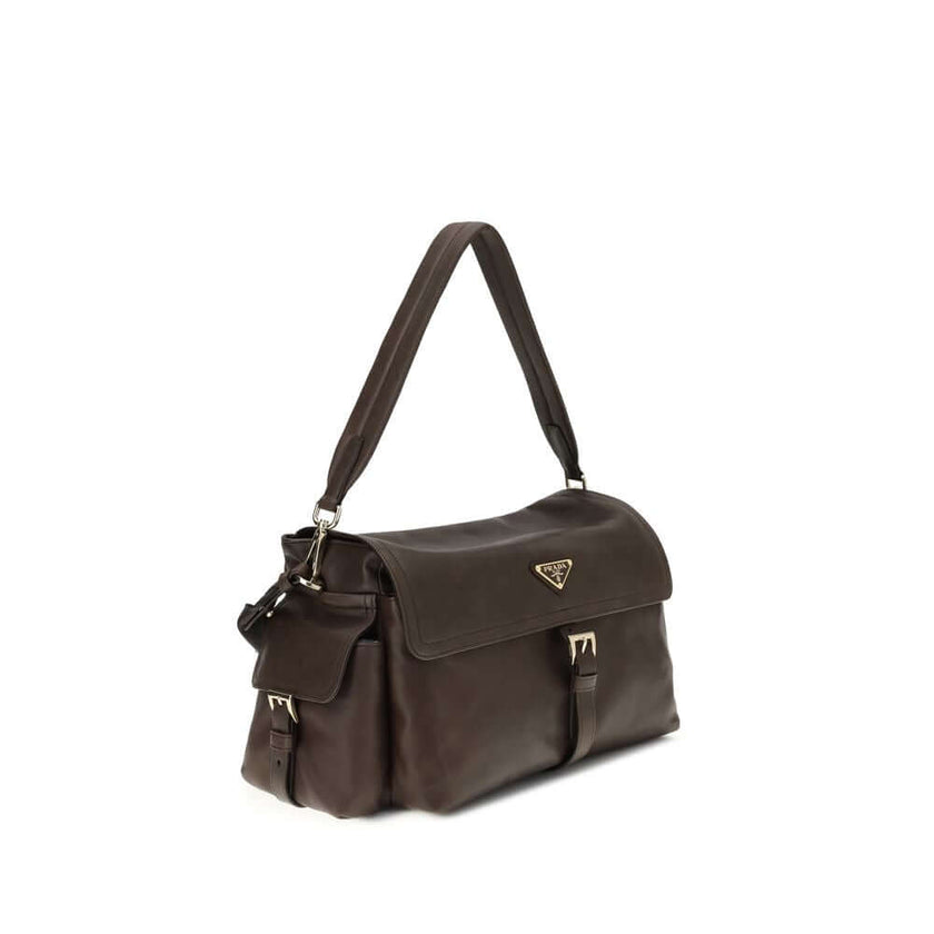 Brown Recycled Polyamide Shoulder BagExplore large Shoulder Bag by Prada is made of Re-Nylon and features a flap with a classic enameled metal triangle logo. It features a padded ribbon handle, front zipper pocket, side flap pockets, and metal trim. The c