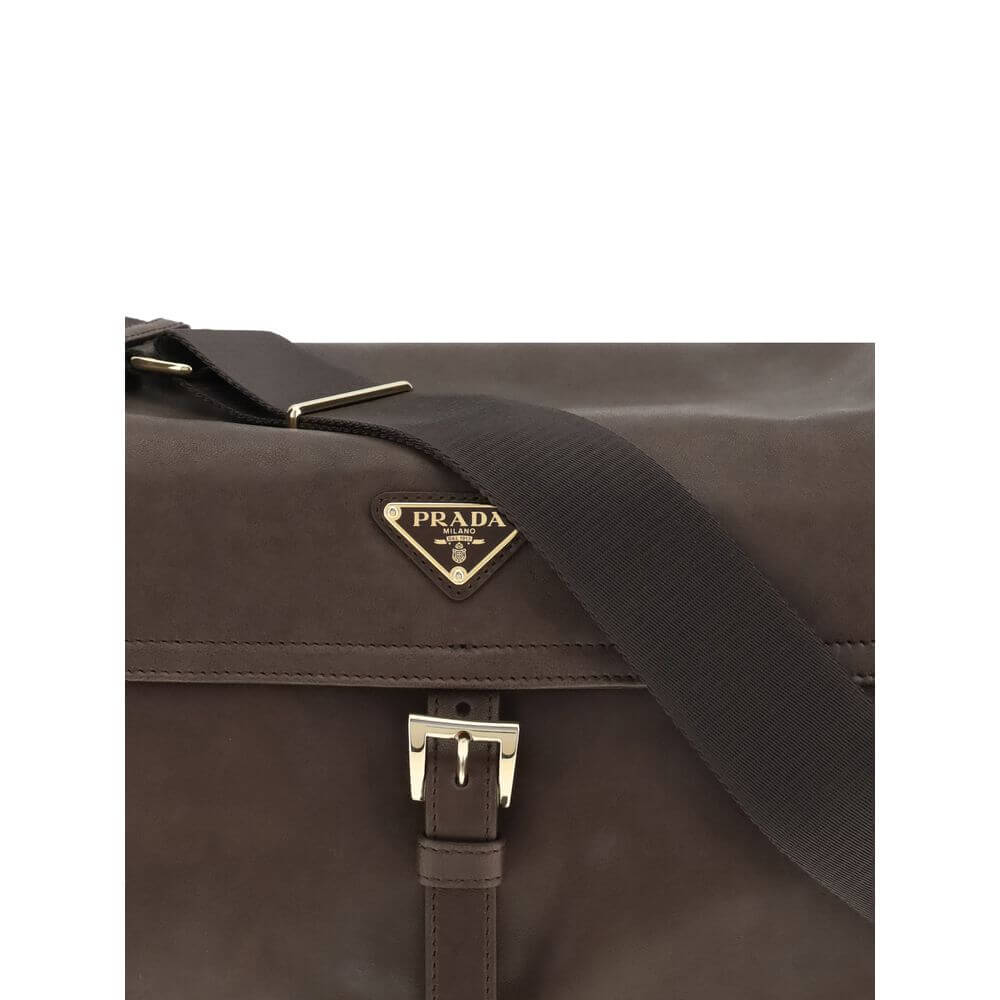 Brown Recycled Polyamide Shoulder BagExplore large Shoulder Bag by Prada is made of Re-Nylon and features a flap with a classic enameled metal triangle logo. It features a padded ribbon handle, front zipper pocket, side flap pockets, and metal trim. The c