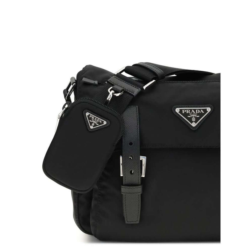 Black Polyamide Shoulder BagExplore medium Shoulder Bag by Prada is made of Re-Nylon and finished with metal details. It features a front zippered pocket, enameled triangle logo flap, and zipper and strap closure. The interior, also made of Re-Nylon, incl