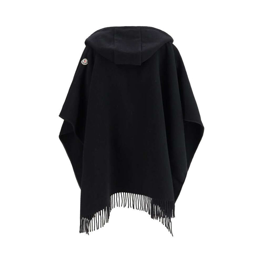 Wool CapeThe wool Cape by Moncler, defined by an elegant draped design that makes it a versatile layering piece for every season. Crafted from soft wool with light padding, it features a nylon laqué belt to define the silhouette, fringed edges, and the ic