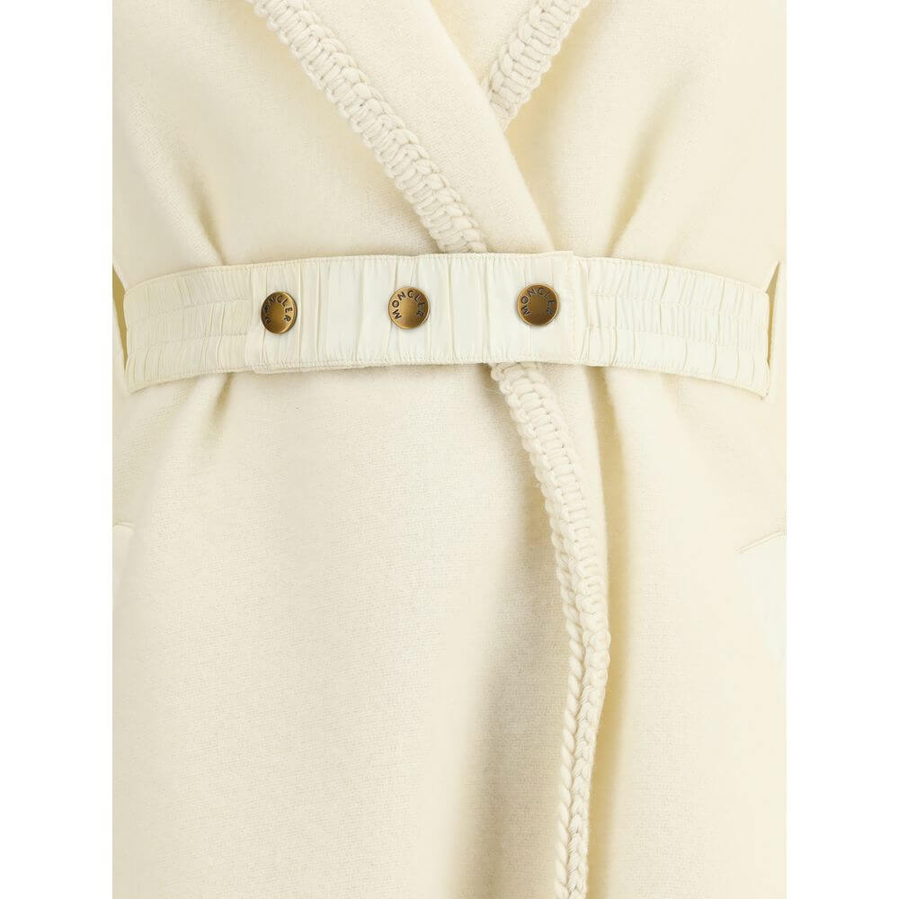 Cream Fleece Wool CoatThe wool Cape by Moncler, defined by an elegant draped design that makes it a versatile layering piece for every season. Crafted from soft wool with light padding, it features a nylon laqué belt to define the silhouette, fringed edge