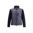 Panelled JacketThe panelled Jacket by Moncler Grenoble crafted from a wool blend, featuring a down-feather padded design that alternates quilted sections with knitted panels. It comes with a high neck, front zip fastening, long sleeves, and ribbed cuffs a
