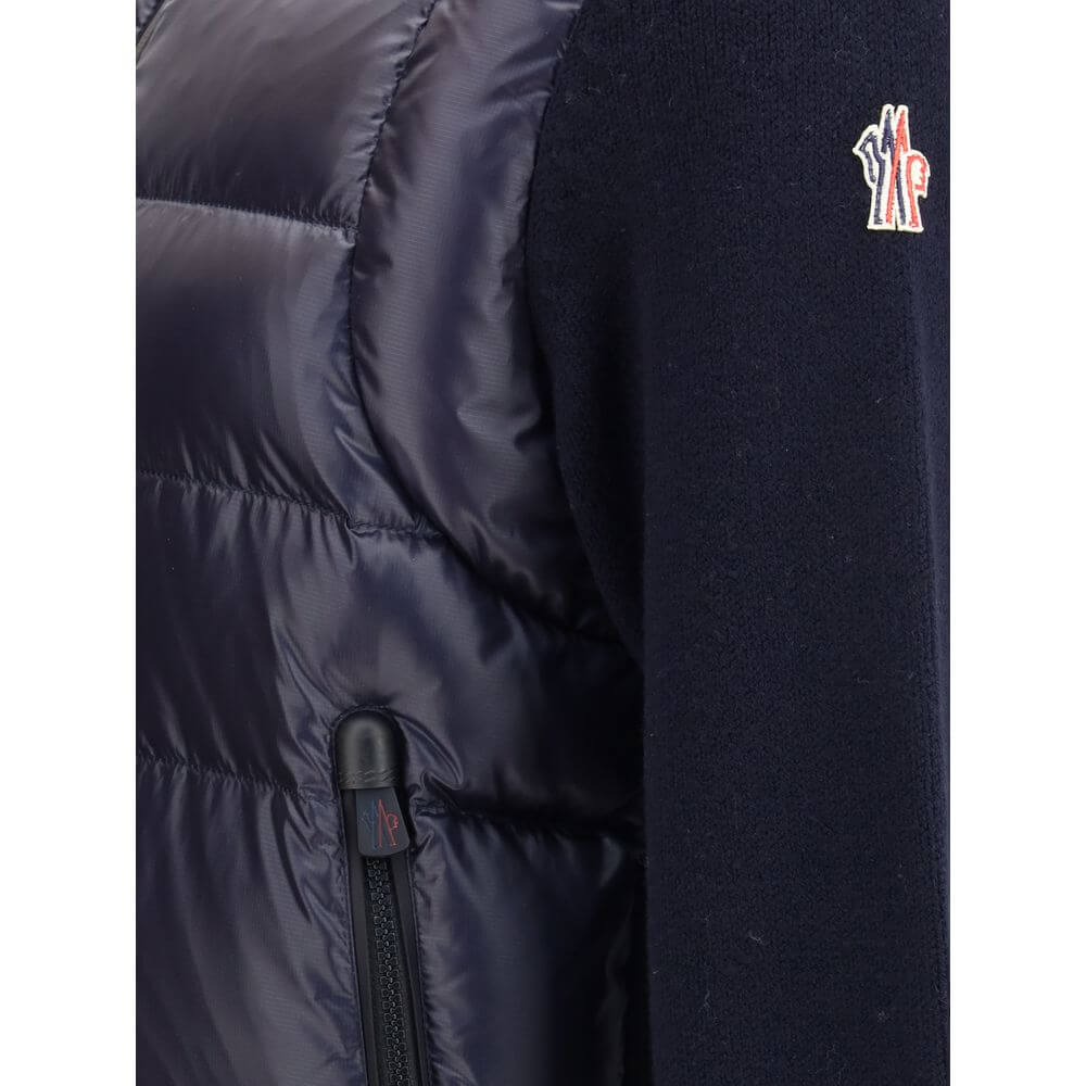 Panelled JacketThe panelled Jacket by Moncler Grenoble crafted from a wool blend, featuring a down-feather padded design that alternates quilted sections with knitted panels. It comes with a high neck, front zip fastening, long sleeves, and ribbed cuffs a