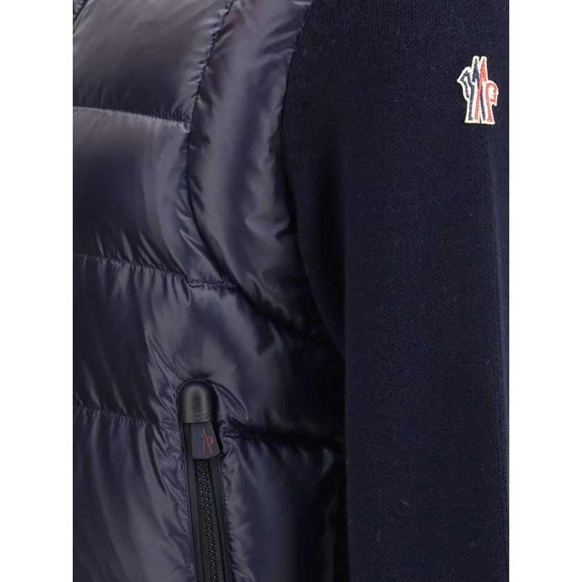Panelled JacketThe panelled Jacket by Moncler Grenoble crafted from a wool blend, featuring a down-feather padded design that alternates quilted sections with knitted panels. It comes with a high neck, front zip fastening, long sleeves, and ribbed cuffs a