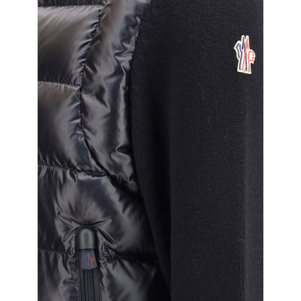 Panelled JacketThe panelled Jacket by Moncler Grenoble crafted from a wool blend, featuring a down-feather padded design that alternates quilted sections with knitted panels. It comes with a high neck, front zip fastening, long sleeves, and ribbed cuffs a
