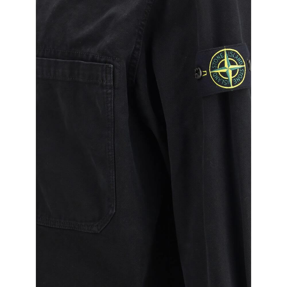 Black Cotton ShirtThe Stone Island Overshirt, crafted from 100% black cotton, is a versatile essential that blends functionality with contemporary style. Featuring a button fastening, two chest patch pockets, and the iconic logo patch on the left sleeve,
