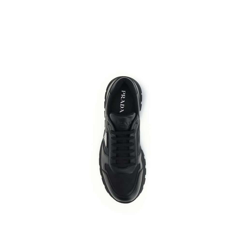 Black Recycled Polyamide Athletic SneakersSneakers by Prada, made of Re-Nylon and brushed leather, combine contemporary style and innovative materials. Equipped with laces, they feature an enameled triangle logo on the upper and screen-printed Prada Milan