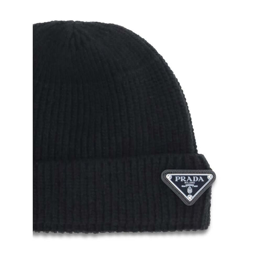 Black Fleece Wool BeaniePrada’s beanie Hat with logo plaque is an essential accessory with distinctive character. Made with ribbed lapels for a snug and comfortable fit, it is embellished with the iconic triangular side plaque, a symbol of the brand’s min