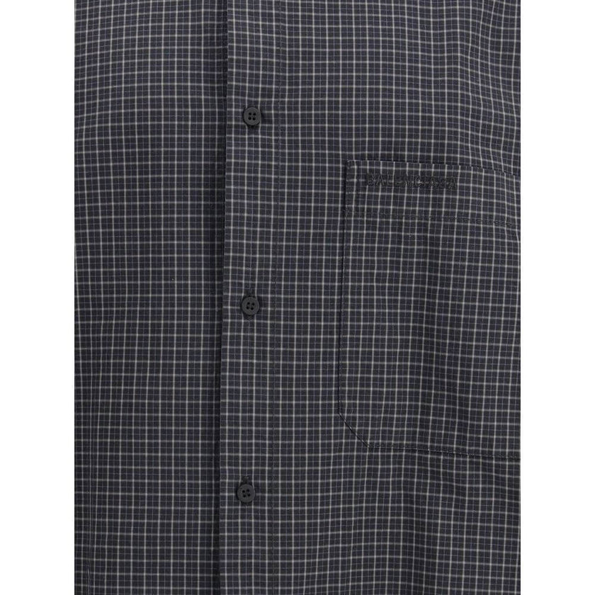 Black Wool Pattern ShirtThe oversized checked Shirt by Balenciaga is crafted from checked wool-blend flannel, reimagining a classic silhouette with a modern oversized cut. It features a button-down collar, seven front buttons engraved with Balenciaga, a c