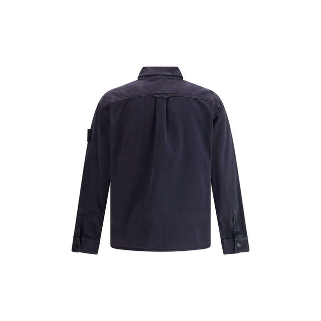 Blue Cotton Dress ShirtThe Stone Island Overshirt, crafted from 100% black cotton, is a versatile essential that blends functionality with contemporary style. Featuring a button fastening, two chest patch pockets, and the iconic logo patch on the left sle