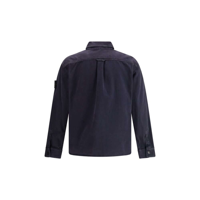Blue Cotton Dress ShirtThe Stone Island Overshirt, crafted from 100% black cotton, is a versatile essential that blends functionality with contemporary style. Featuring a button fastening, two chest patch pockets, and the iconic logo patch on the left sle