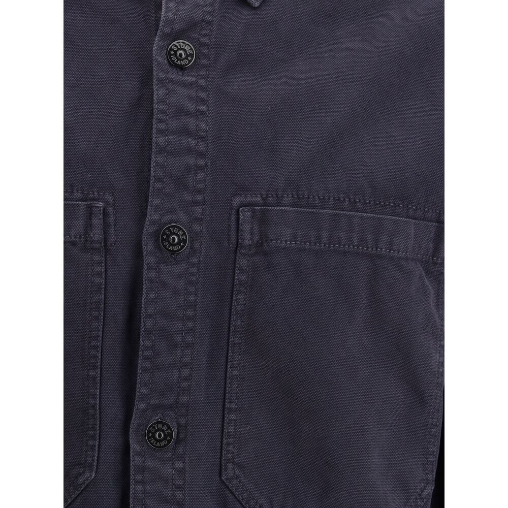 Blue Cotton Dress ShirtThe Stone Island Overshirt, crafted from 100% black cotton, is a versatile essential that blends functionality with contemporary style. Featuring a button fastening, two chest patch pockets, and the iconic logo patch on the left sle