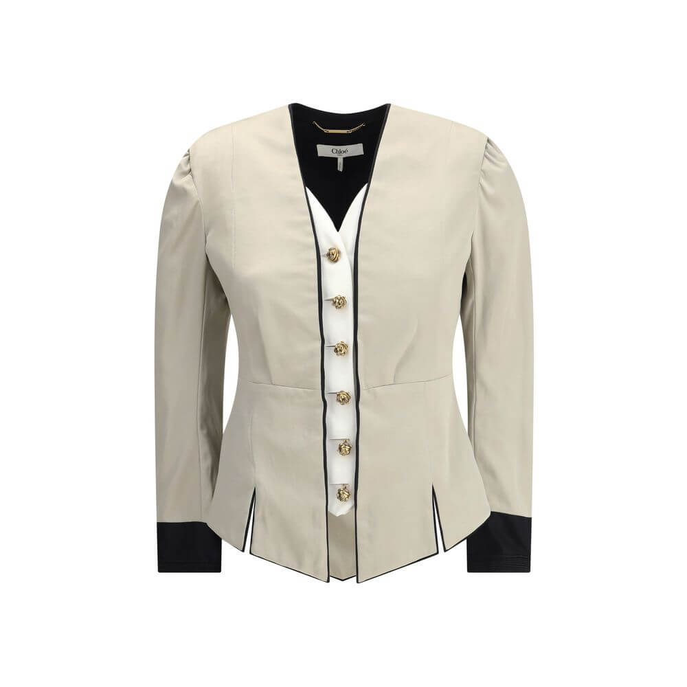 Silver Silk CoatThe Tailored Silk Jacket by Chloé reimagines classic elegance with refined details and a strong architectural touch. Its deep V-neckline is layered with a contrasting white placket, accentuated by gold-tone floral buttons for a luminous fi