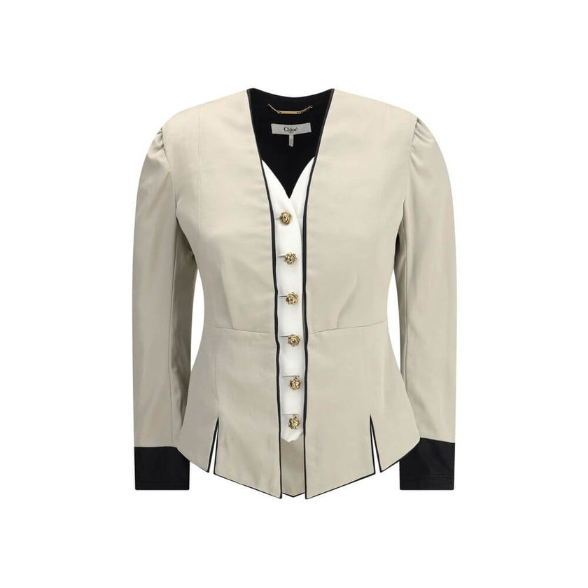 Silver Silk CoatThe Tailored Silk Jacket by Chloé reimagines classic elegance with refined details and a strong architectural touch. Its deep V-neckline is layered with a contrasting white placket, accentuated by gold-tone floral buttons for a luminous fi